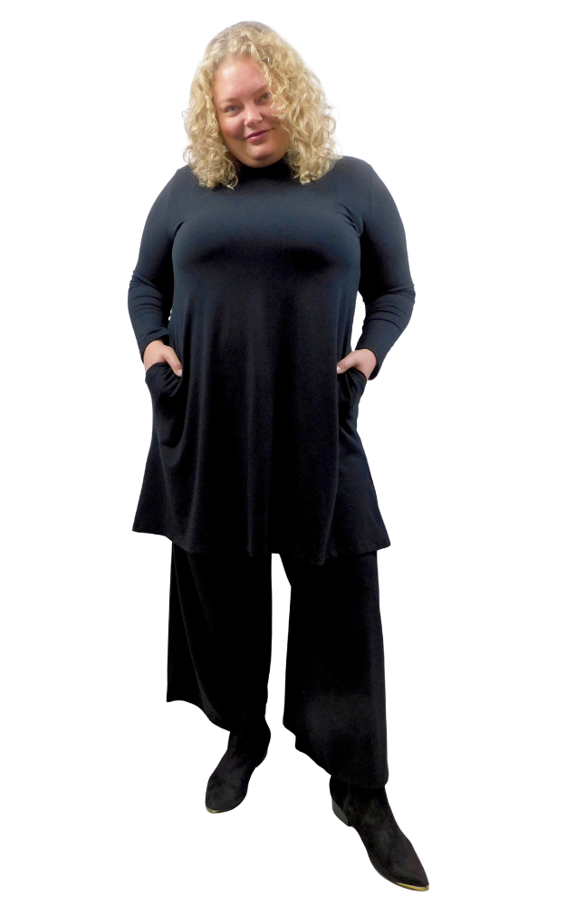 A woman modeling a long-sleeve, high-neck turtleneck tunic dress in Black  styled with wide black pants