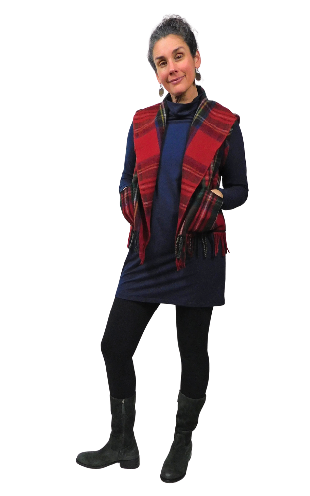 Person wearing a blue dress, red tartan vest, and green boots on a white background