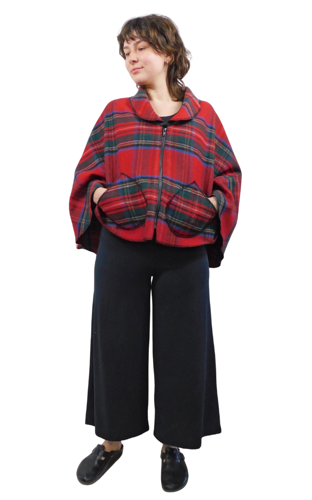 Person wearing a red and blue and green tartan plaid cape on a white background