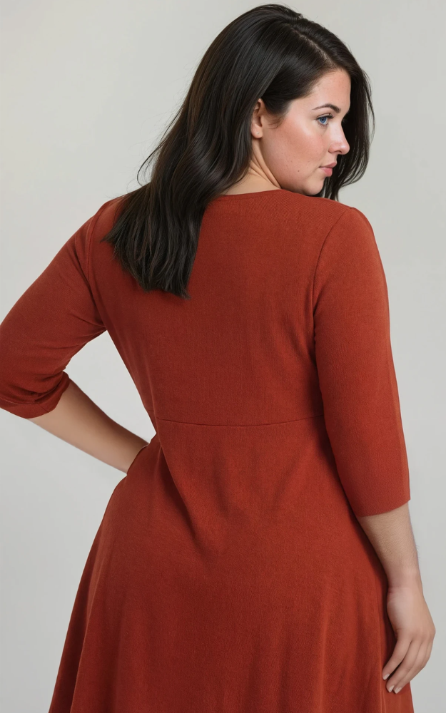 Woman wearing a rust-colored dress against a plain background