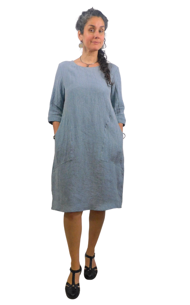 Woman wearing a striped blue and white dress standing against a white background