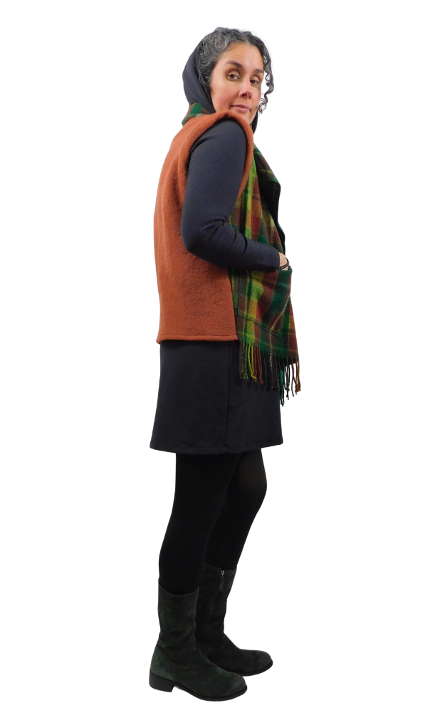 Person wearing a brown vest, dark dress, black boots, and a colorful scarf on a white background